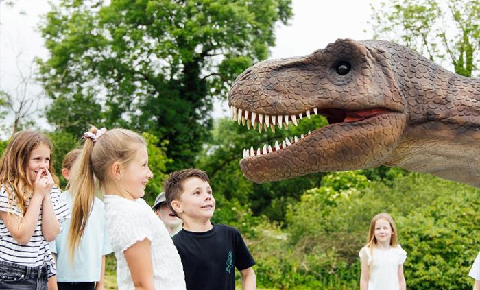 A group of children laughing at Red the T-Rex.